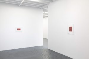 View of two red works on opposing walls.