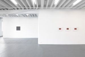Gallery view of two works , one gray, and one red tryptic.
