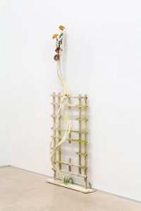 Wooden structure with rope and flowers growing up from it.