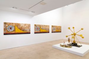 Three landscape paints on wall with large sculptue in the middle of the floor.