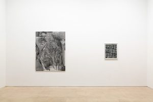 View of two works: Left is a large black and white abstract painting; on the right is a small black and white photograph.
