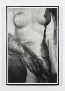Black and white frontal photo of a nude woman partially covered in black paint