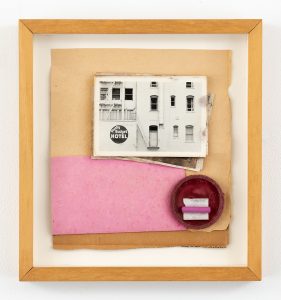 Wooden framed collage made with cardboard, various pink material towards the bottom and a postcard of a hotel facade at the top.