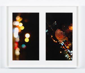 Two photogtaphs of dark streets, street lights, and various reflections of urban landscape in white frame