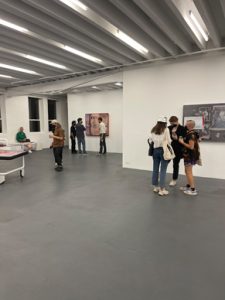 Photograph of visitors viewing Tishan Hsu's solo exhibition "skin-screen-grass" at Miguel Abreu Gallery. A group of people are gathered in front of "Breath 3" while another group is conversing in front of "QMH 6.2.1"