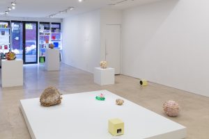 Gallery space with sculptures, wall hangings, and speakers