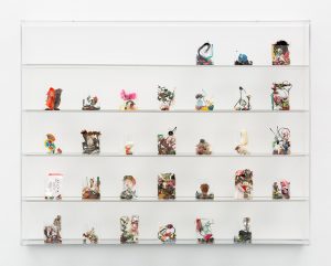 30 small cellophane wrappers containing found material arranged in clear vitrine