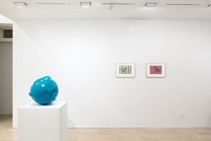 Gallery view from left to right: round turquoise sculpture and two framed watercolors