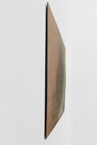 Side view of wooden carved panel showing round bulge.