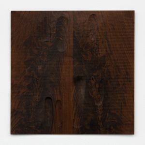 Dark wooden panel with oval indents carved out.