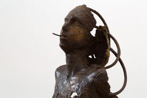 Frontside detail of dark brown previous sculpture of dismembered figure.