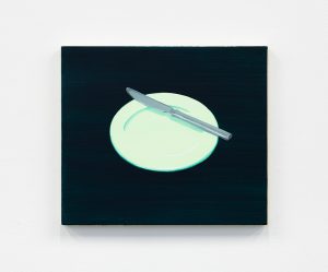 Light green plate with a knife on a dark backdrop.