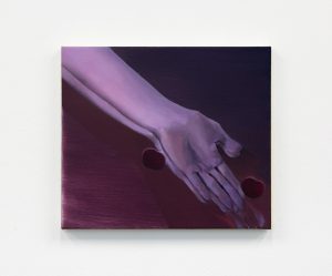 Two hands overlapping, as they are dropping two round ambiguous figures.