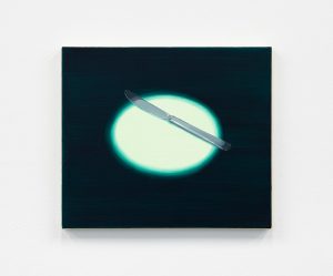 A butter knife hit by a light green stage light.