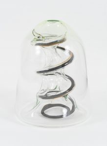A glass dome with hints of greens and a metal spring forced into it from the bottom.