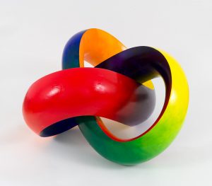 Three-dimensional mobius strip with three twist, painted in a spectrum from red to blue. This angle shows red, purple and green values.