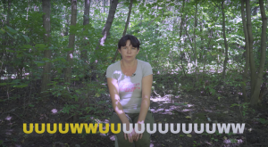 Video frame with a white, brown haired person wearing a T-shirt and pants is sitting facing the camera with a forest in the background. There is a caption that says "UUUUWWUUUUUUUWW"
